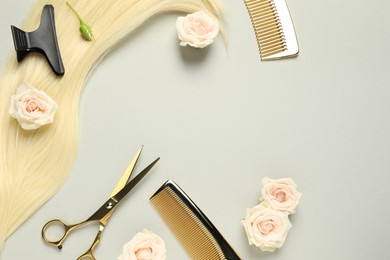 Photo of Flat lay composition with professional hairdresser tools, flowers and blonde hair strand on light grey background. Space for text