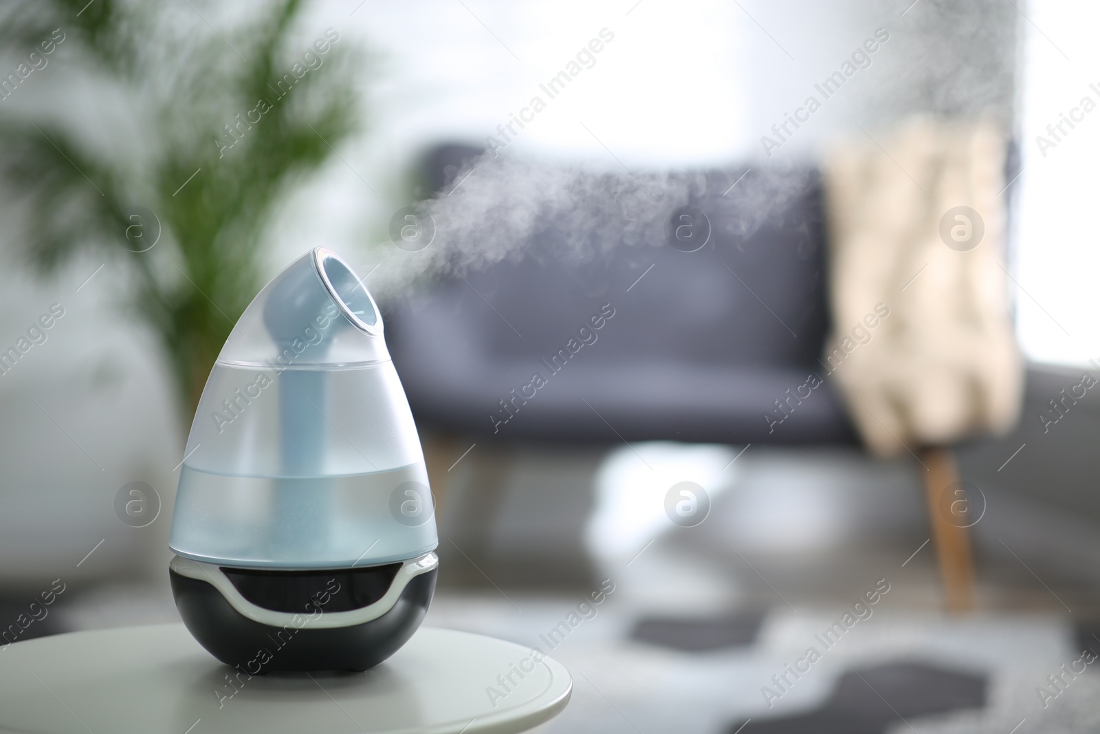 Photo of Modern air humidifier on table indoors. Space for text