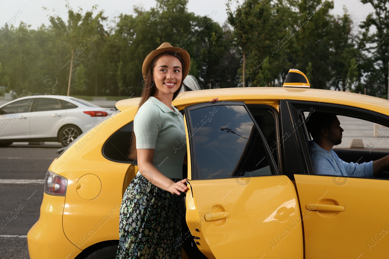 Photo of Beautiful young woman getting in taxi on city street