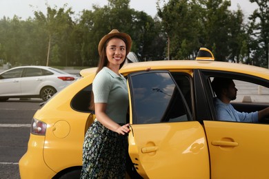 Photo of Beautiful young woman getting in taxi on city street