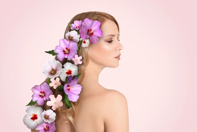 Image of Pretty woman wearing beautiful wreath made of flowers on light pink background