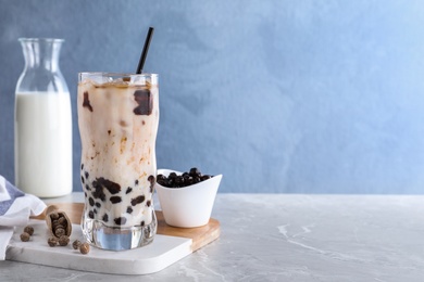Bubble milk tea with tapioca balls on grey marble table against blue background. Space for text