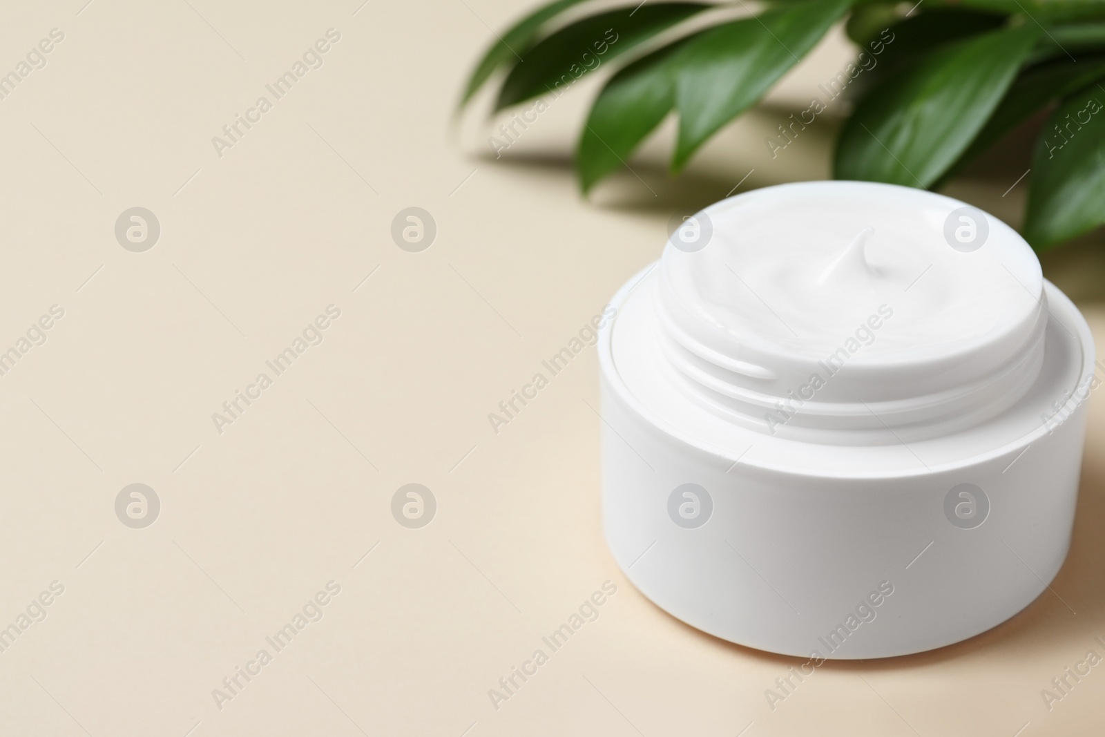 Photo of Open jar of cream on beige background, closeup. Space for text