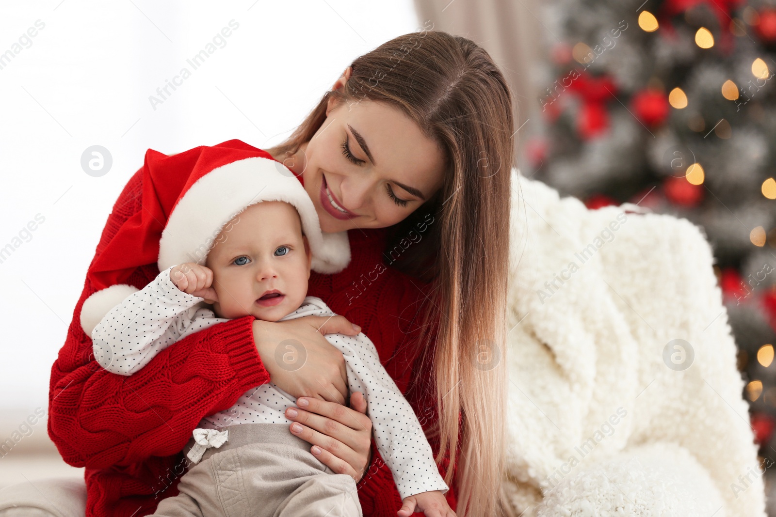 Photo of Happy mother with cute baby in room decorated for Christmas holiday