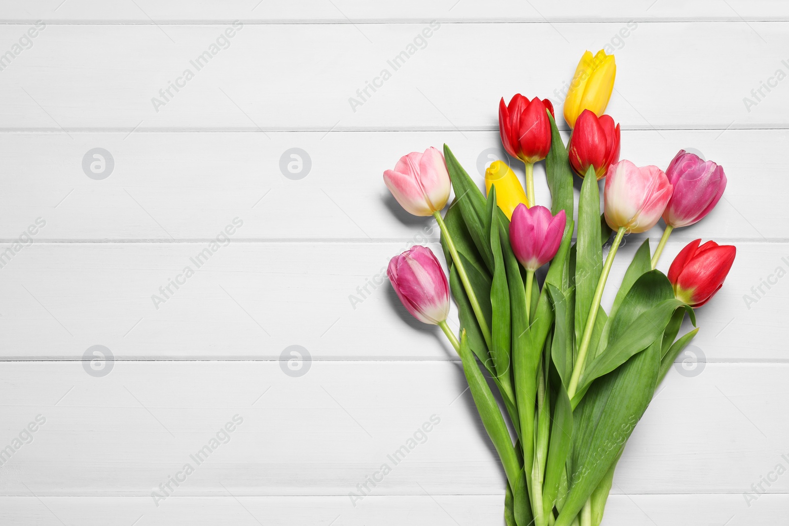 Photo of Beautiful colorful tulip flowers on white wooden table, flat lay. Space for text