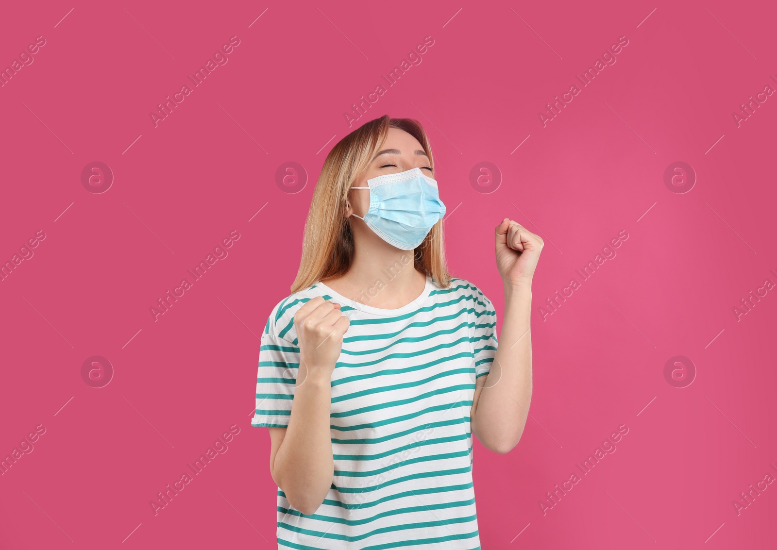 Photo of Emotional woman with protective mask on pink background. Strong immunity concept