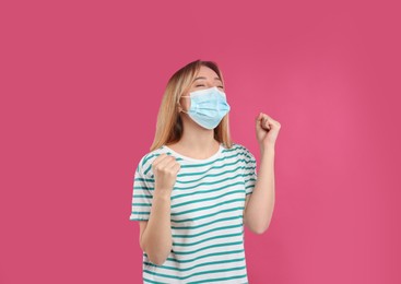 Emotional woman with protective mask on pink background. Strong immunity concept