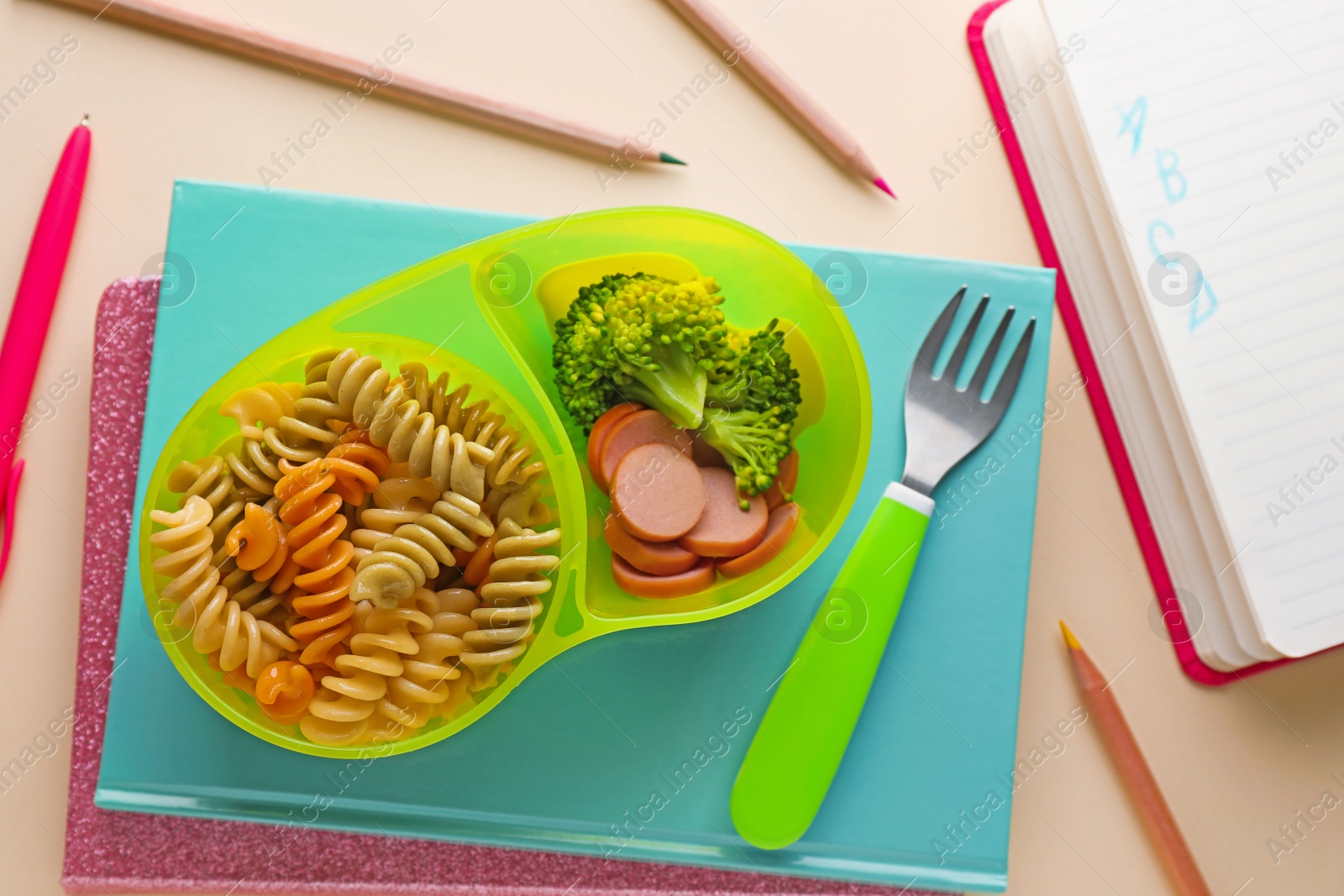 Photo of Bowl with tasty pasta, broccoli and sausage on beige background, flat lay