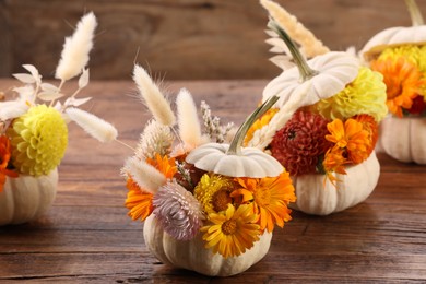 Photo of Composition with small pumpkins, beautiful flowers and spikelets on wooden table, closeup