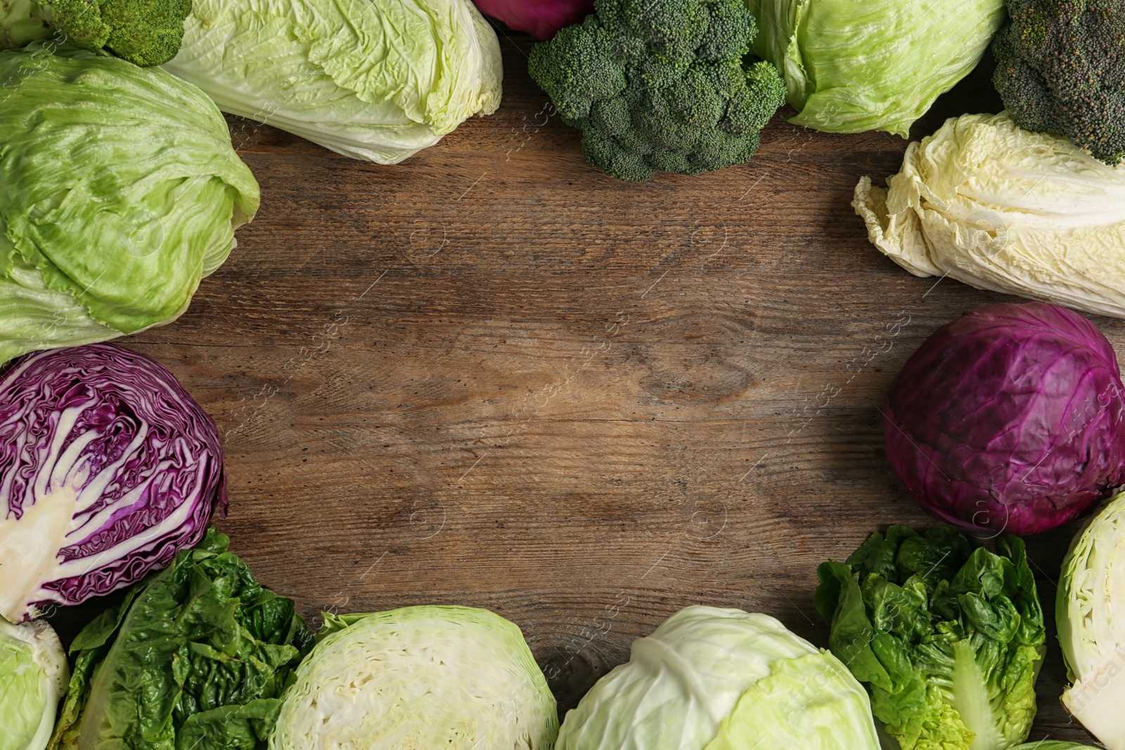 Photo of Frame of different cabbages on wooden background, flat lay. Space for text