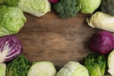 Photo of Frame of different cabbages on wooden background, flat lay. Space for text