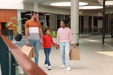 Photo of Family shopping. Happy parents and son with purchases in mall