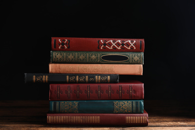 Photo of Collection of different books on wooden table against dark background