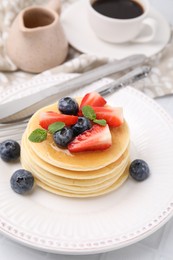 Photo of Delicious pancakes with strawberries, blueberries and mint on white table, closeup