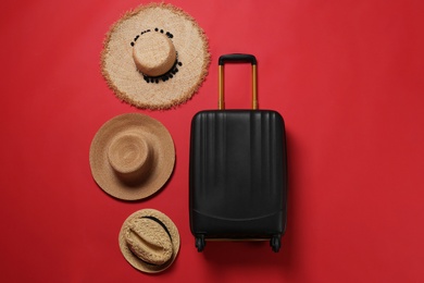 Photo of Stylish suitcase and straw hats on color background, top view