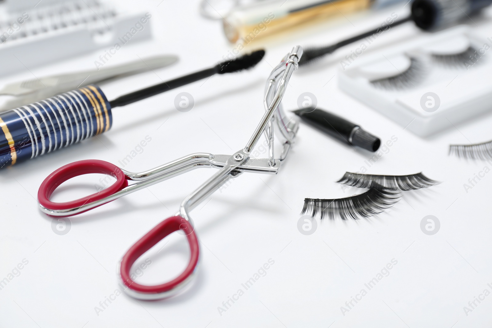 Photo of False eyelashes, curler and mascara brush on white background