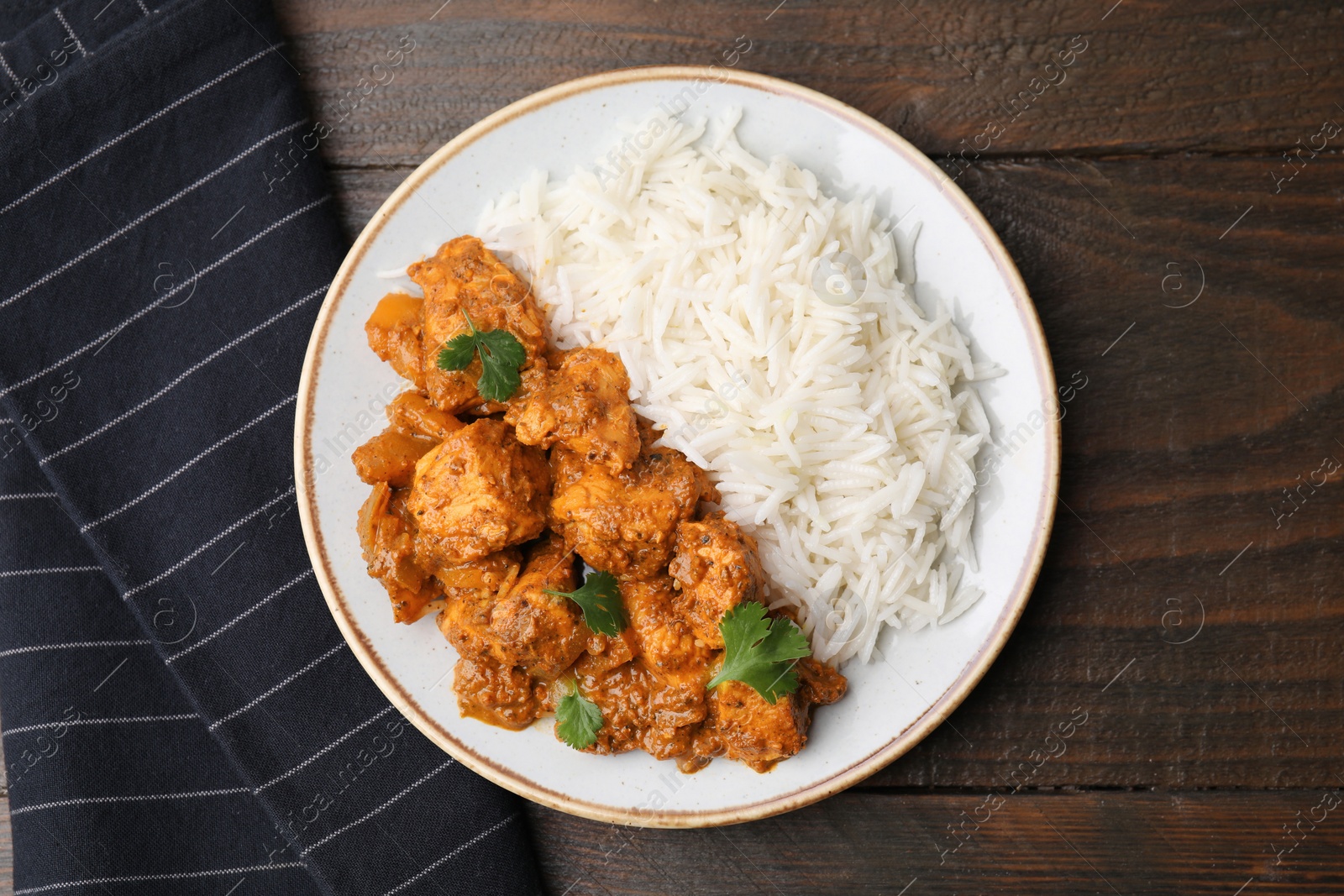 Photo of Delicious chicken curry with rice on wooden table, top view