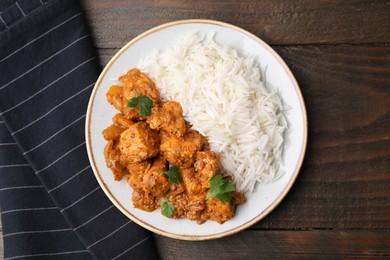 Photo of Delicious chicken curry with rice on wooden table, top view