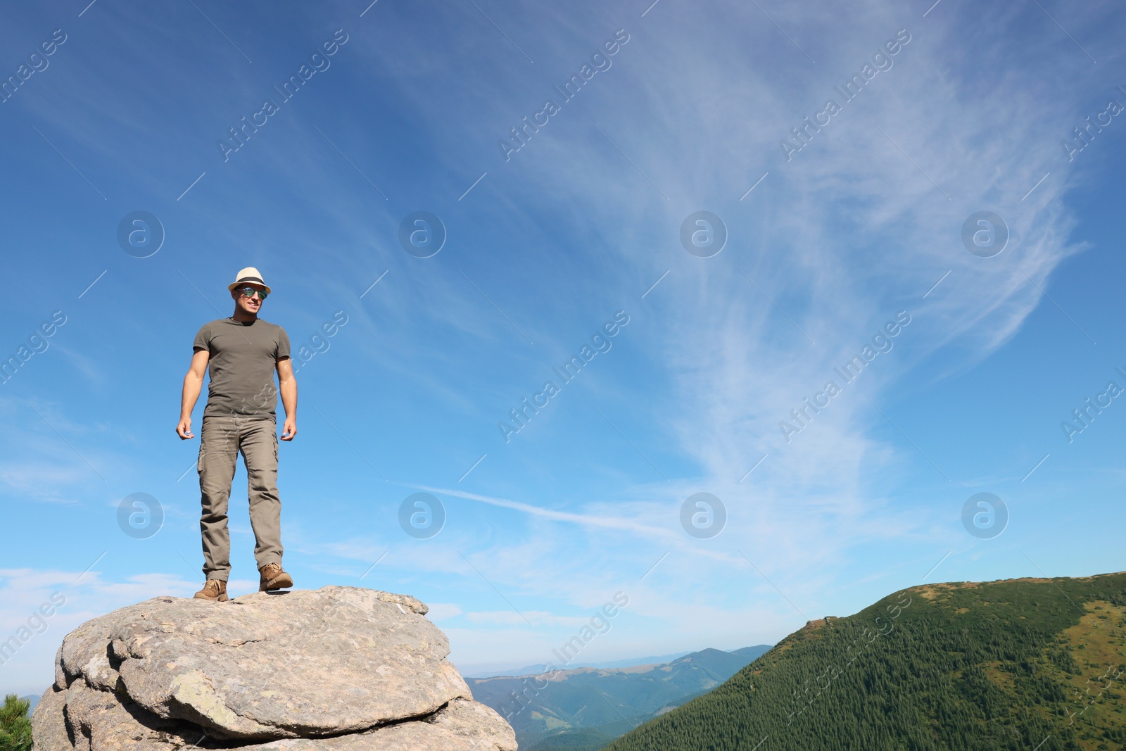 Photo of Man enjoying picturesque view on cliff in mountains. Space for text