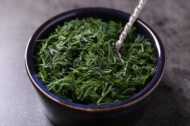 Photo of Fresh cut dill in bowl on grey textured table, closeup