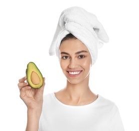 Photo of Happy young woman with towel holding avocado on white background. Organic face mask