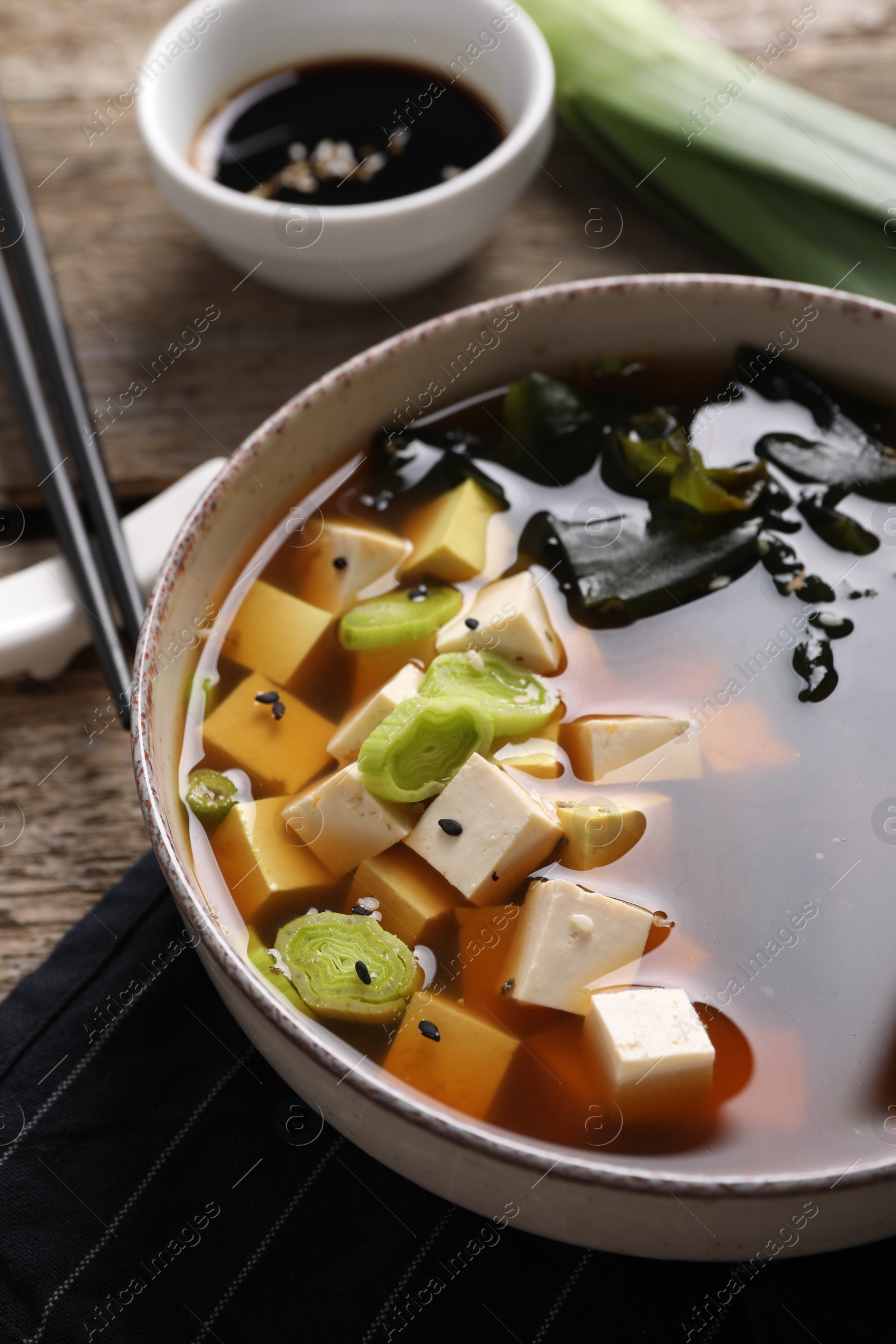 Photo of Bowl of delicious miso soup with tofu on table, closeup