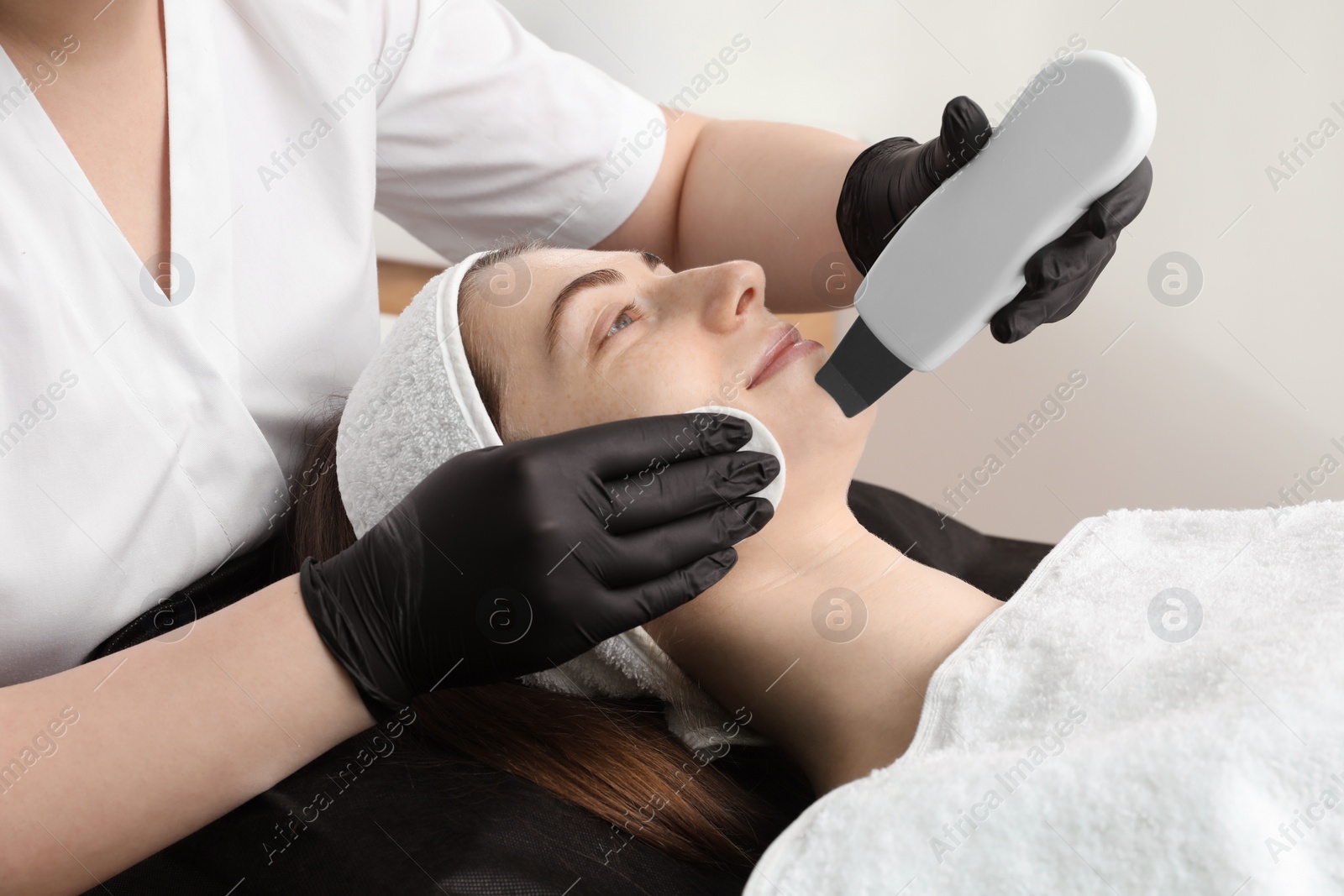 Photo of Cosmetologist using ultrasonic scrubber, closeup. Client having cleansing procedure in clinic