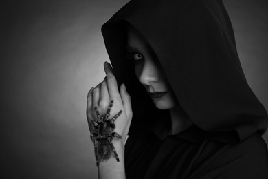 Photo of Mysterious witch with spooky spider on dark background, space for text. Black and white effect