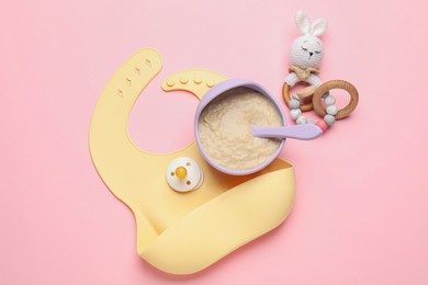 Photo of Healthy baby food in bowl and accessories on pink background, flat lay