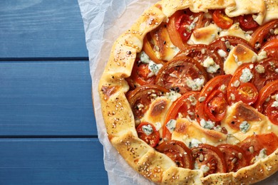 Photo of Tasty galette with tomato and cheese (Caprese galette) on blue wooden table, top view. Space for text
