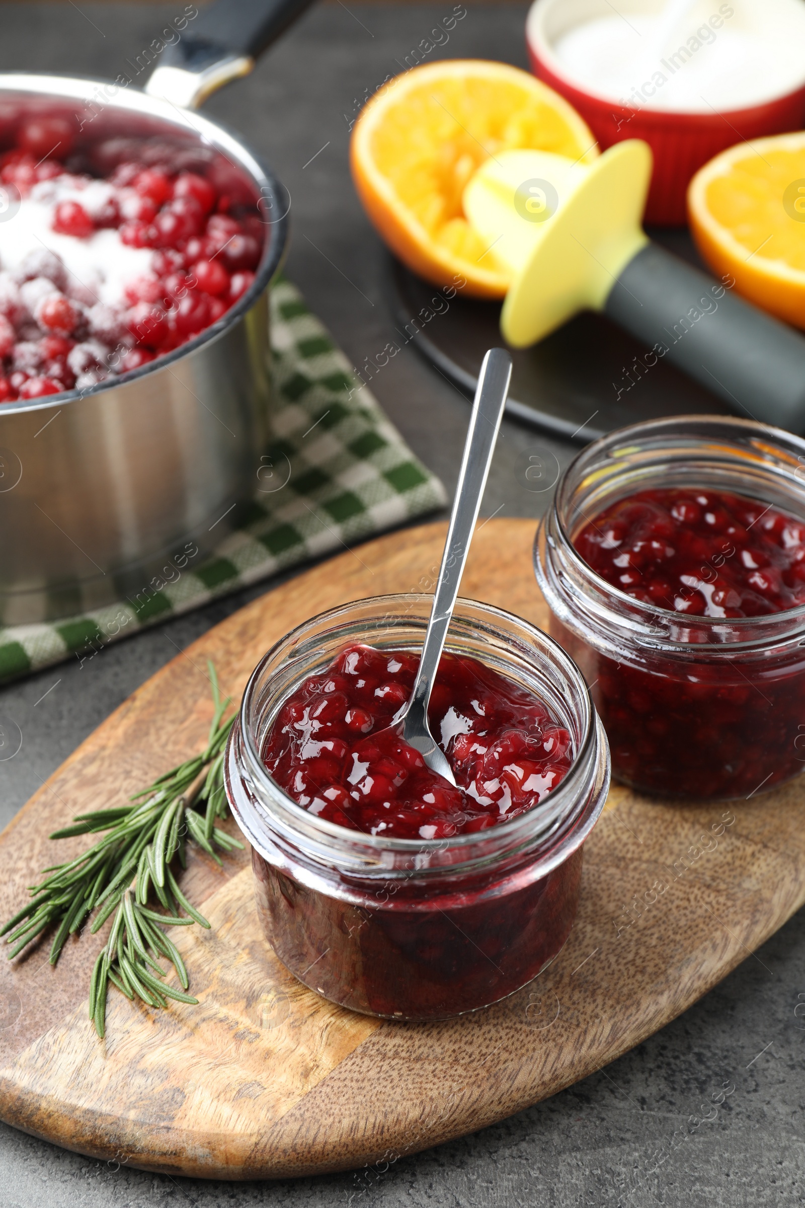 Photo of Fresh cranberry sauce in glass jars served on gray table