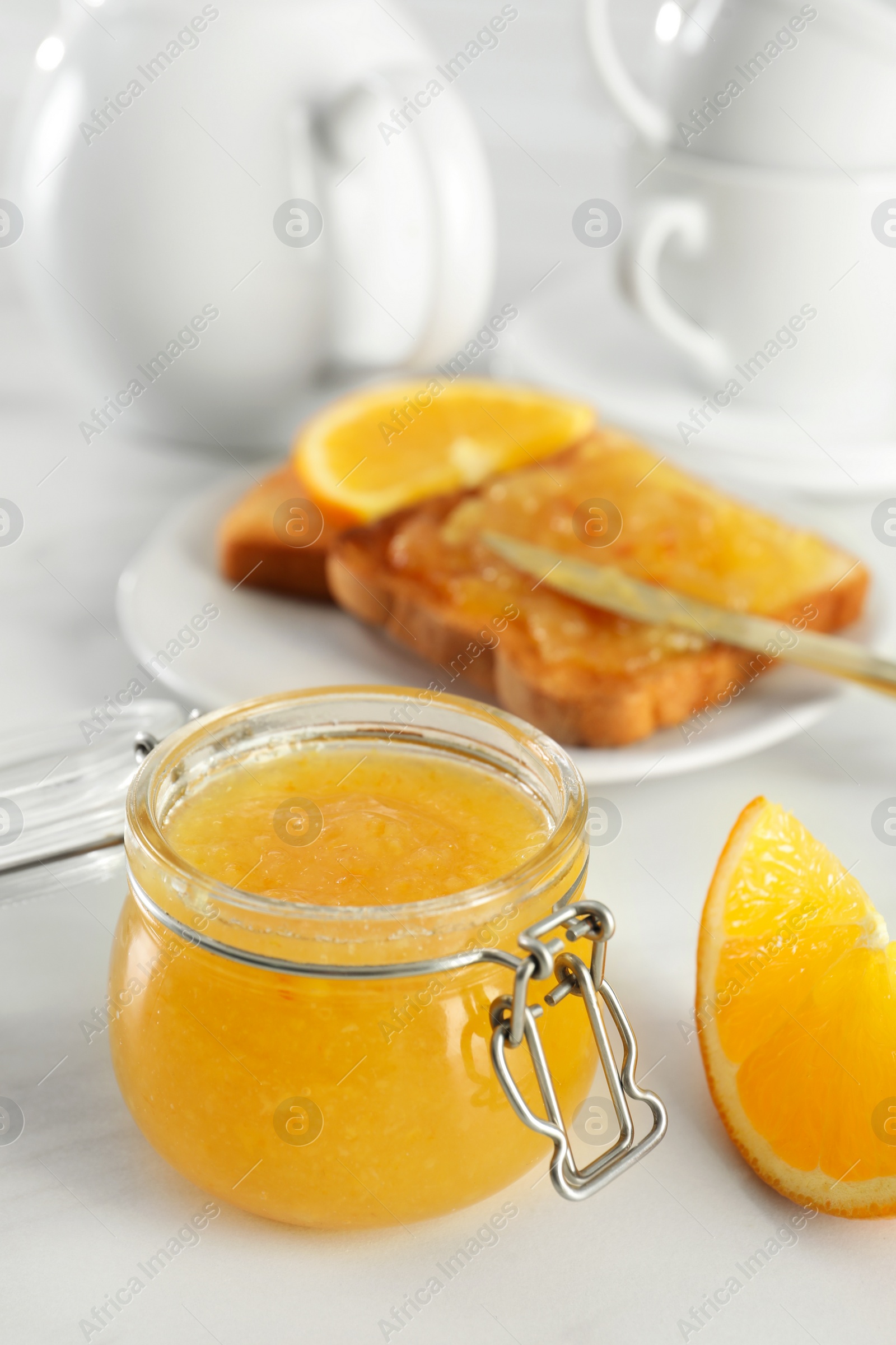 Photo of Delicious orange marmalade and citrus fruit slice on white table. Space for text