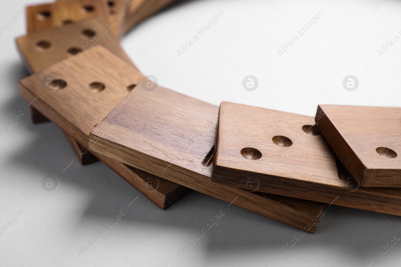 Photo of Fallen wooden domino tiles on light grey background, closeup