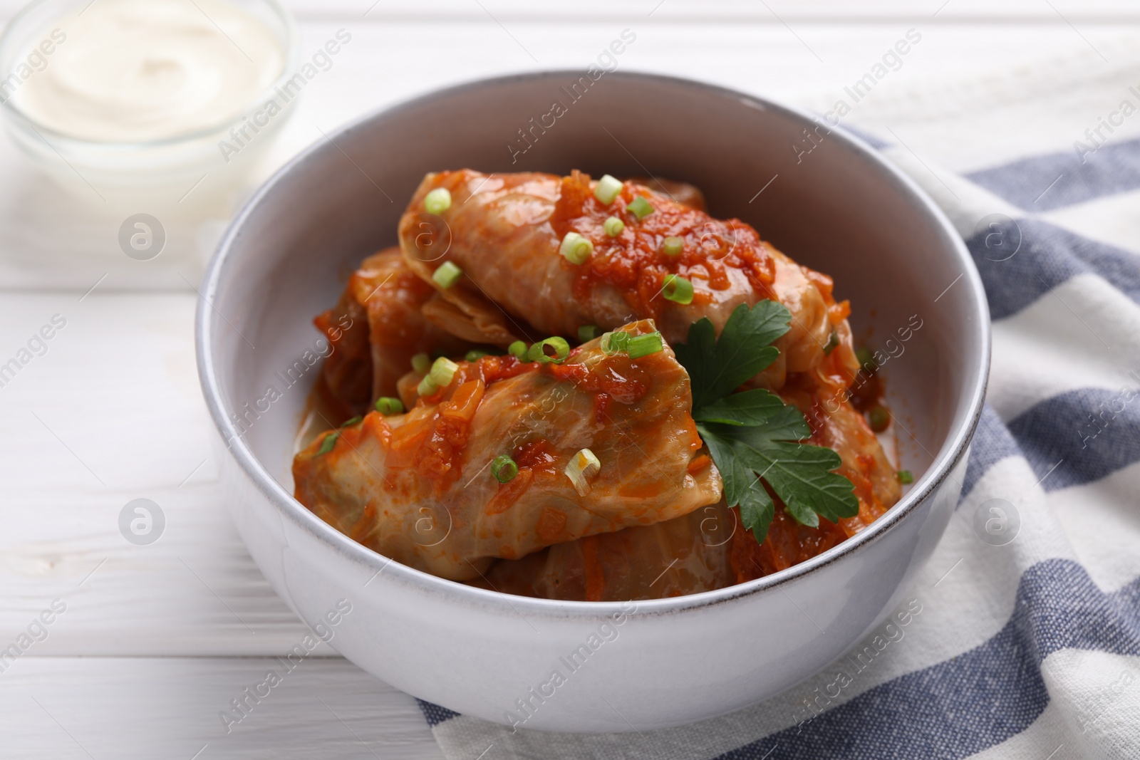 Photo of Delicious stuffed cabbage rolls cooked with homemade tomato sauce on white wooden table, closeup