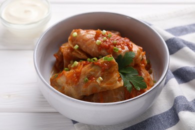 Photo of Delicious stuffed cabbage rolls cooked with homemade tomato sauce on white wooden table, closeup