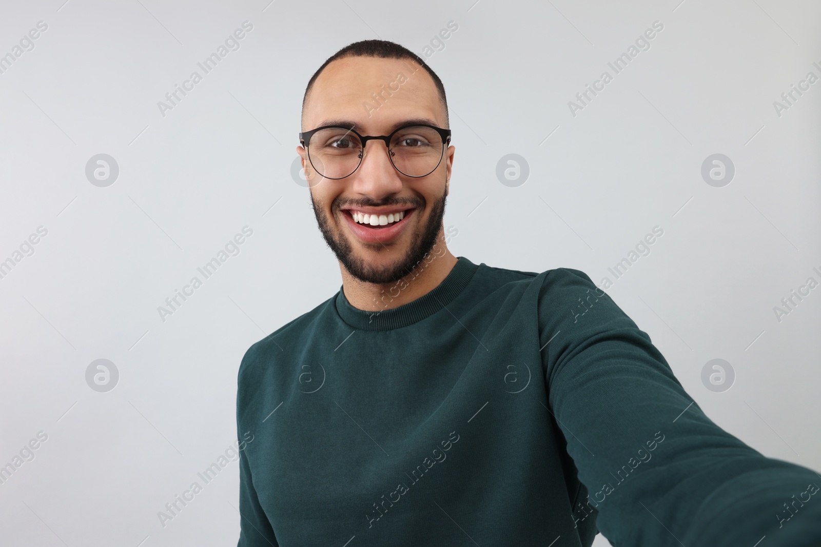 Photo of Smiling young man taking selfie on grey background