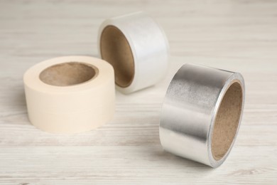 Photo of Three different rolls of adhesive tape on wooden table