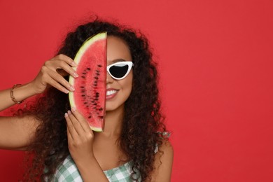 Beautiful young African American woman with slice of watermelon on red background. Space for text