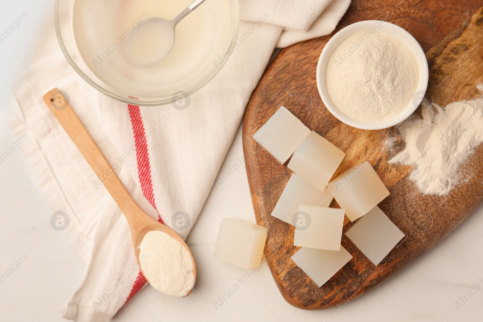 Photo of Agar-agar jelly cubes and powder on white marble table, flat lay