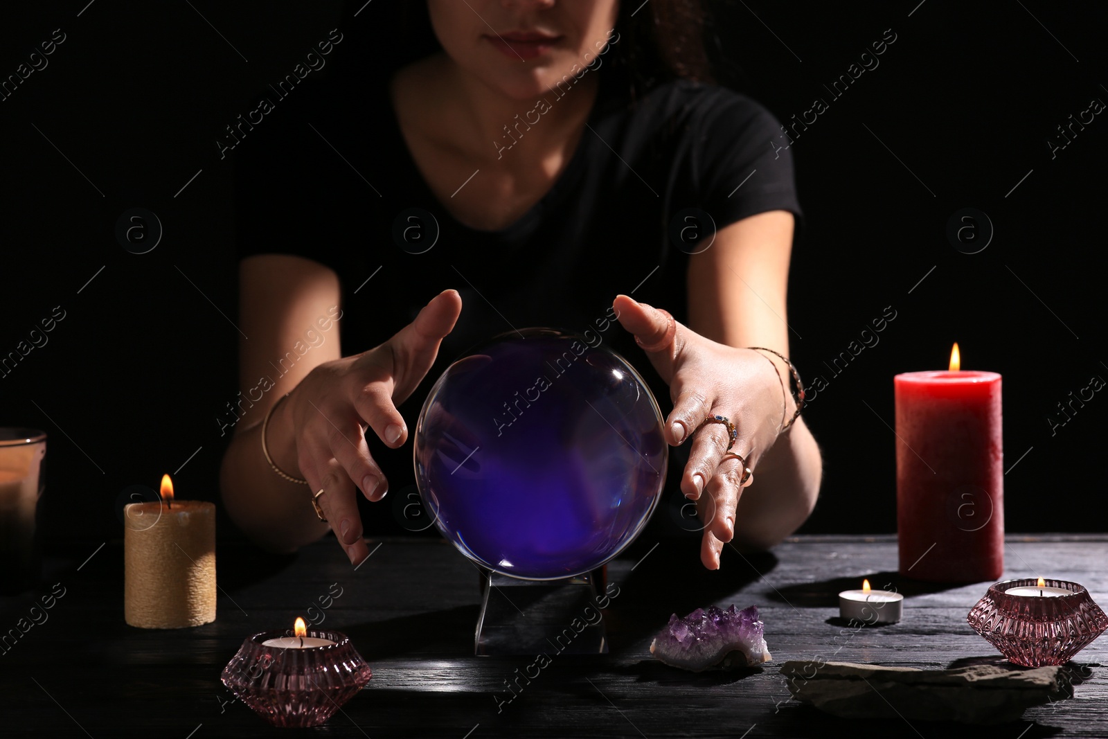 Photo of Soothsayer using crystal ball to predict future at table in darkness, closeup