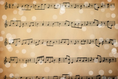 Image of Top view of old sheet with Christmas music notes as background, bokeh effect