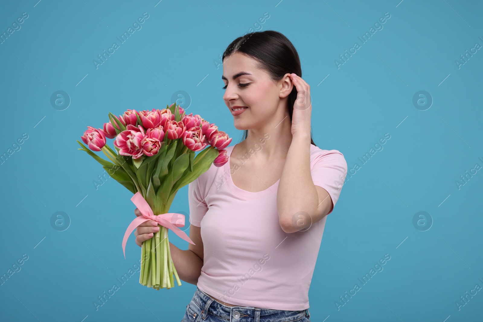 Photo of Happy young woman with beautiful bouquet on light blue background