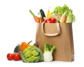 Photo of Paper bag with fresh vegetables and bottle of juice on white background