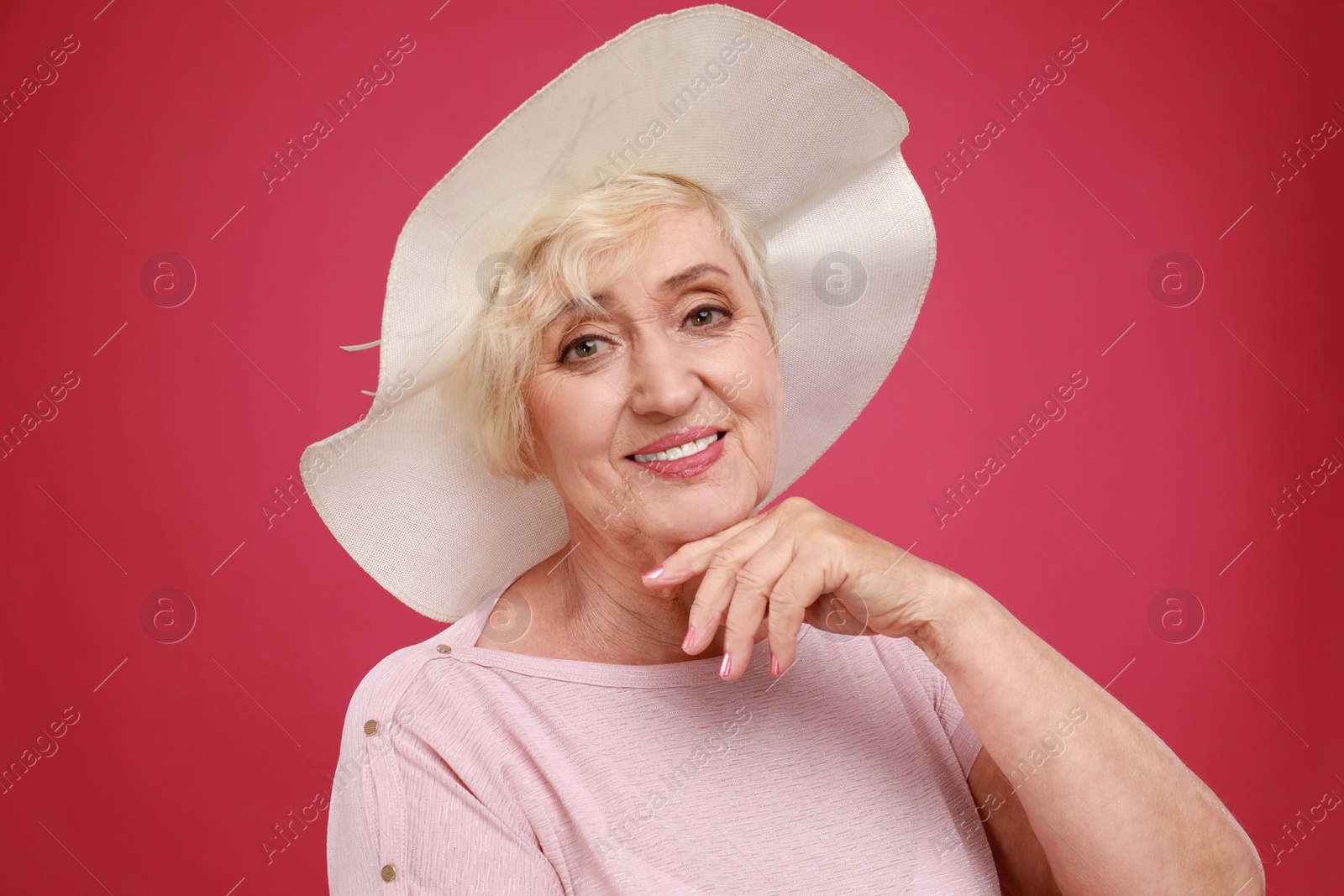 Photo of Senior woman with hat on crimson background