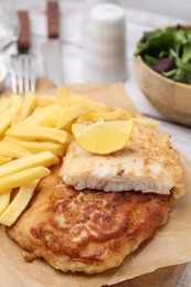 Photo of Tasty soda water battered fish, potato chips and lemon slice on table, closeup