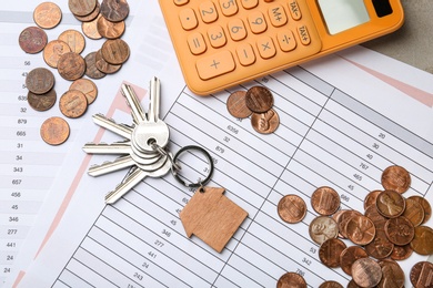 Photo of Calculator with documents, keys and coins on table, top view. Real estate agent service