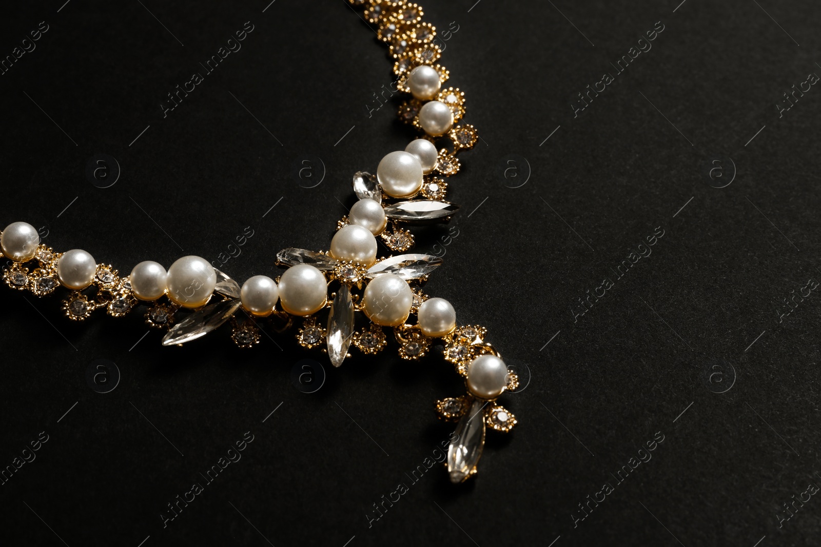 Photo of Stylish necklace with gemstones on black background, space for text. Luxury jewelry