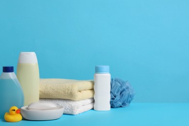 Baby cosmetic products, bath duck, sponge and towels on light blue background. Space for text