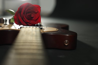 Photo of Beautiful rose and electric guitar on black background, closeup. Space for text