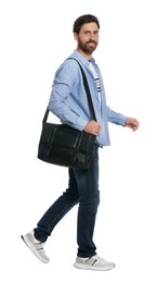 Handsome man with bag in stylish outfit walking on white background